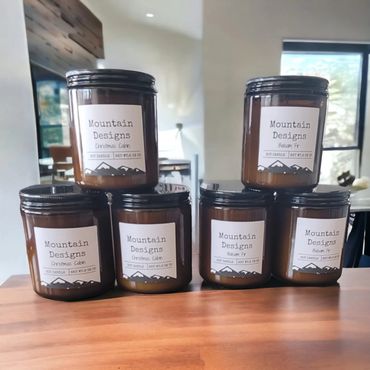 Six Mountain Designs soy candles in Christmas Cabin and Balsam Fir scents on a wooden table.