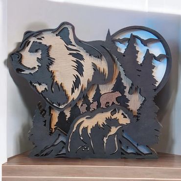 Intricately carved wooden bear art with forest and mountain details.