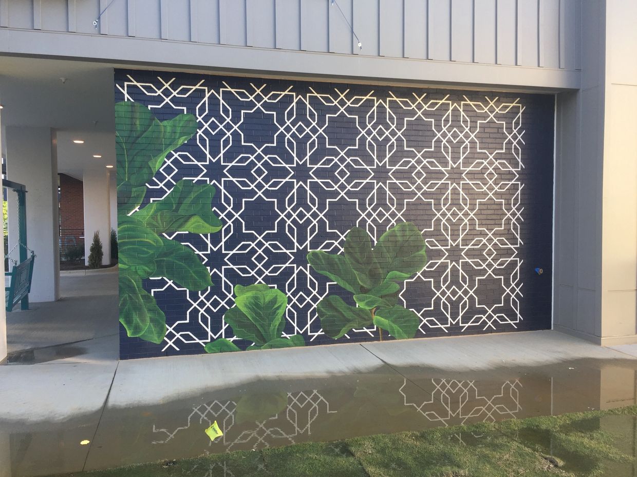 Mural with a blue and white geometric background and green leaves.