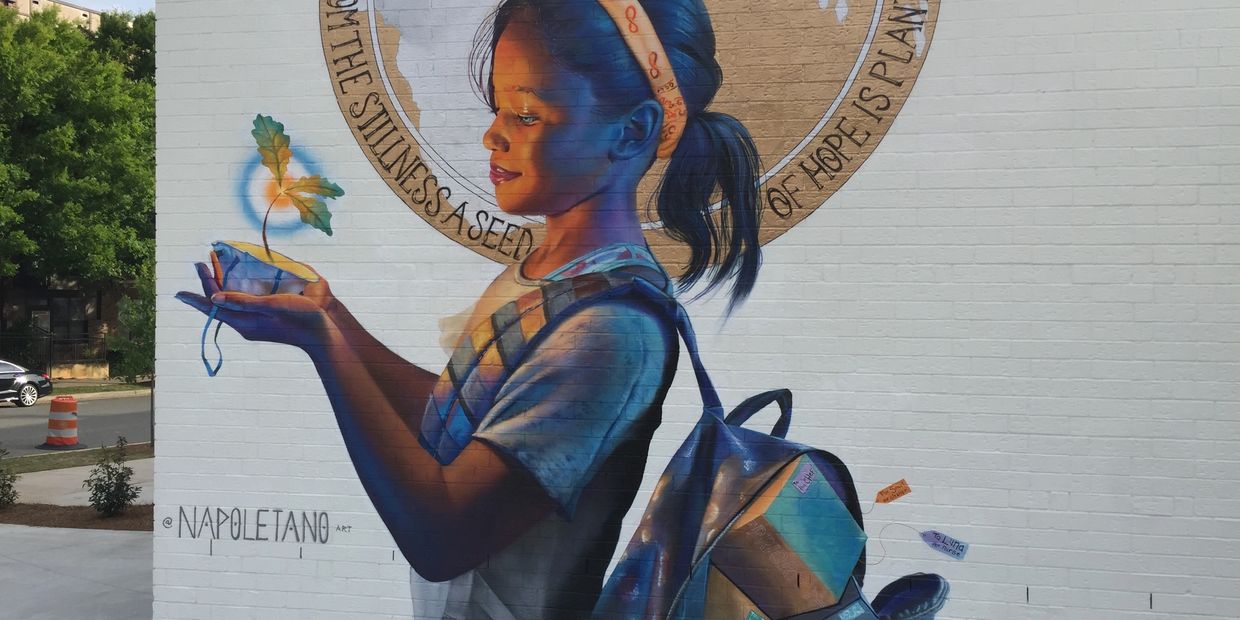 Mural with a smiling little girl holding a white mask with a flower growing out of it.