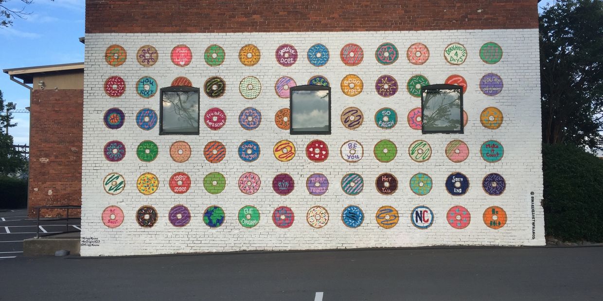 Mural of 12 columns and 6 rows of donuts painted in different designs against a white background.