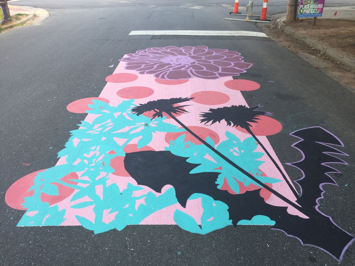 Street mural with large purple flower, a pink and turquoise background, dots and a black dandelion