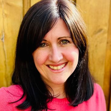 Smiling woman with dark hair wearing a pink top.