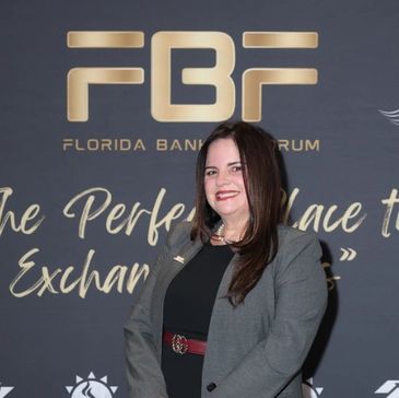 Woman smiling at a Florida Bank Forum event with a professional backdrop.