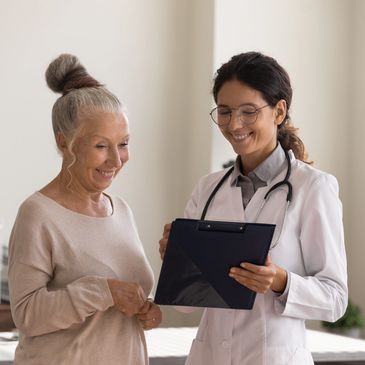 Smiling female doctor showing her smiling senior patient results on a clipboard.
