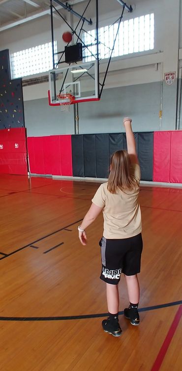 A person shooting a basketball in an indoor gym.