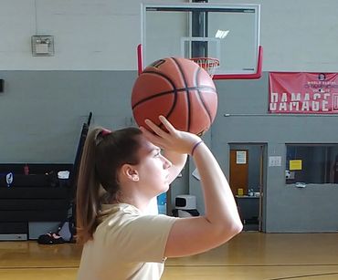 Young woman preparing to shoot a basketball in a gymnasium.