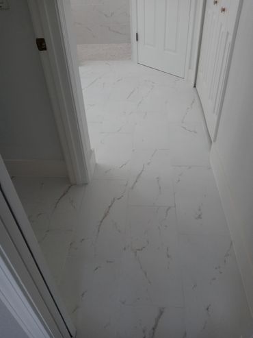White marble floor tiles in a hallway leading to a bathroom.