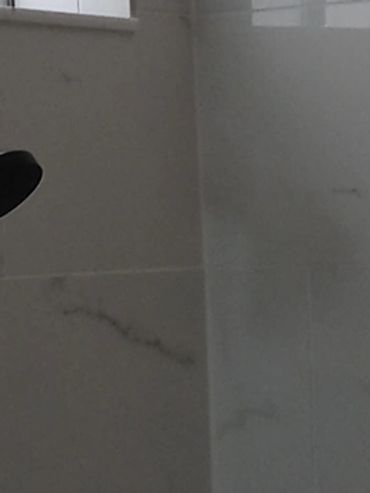 Modern bathroom shower area with marble tiles and dual showerheads.