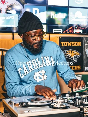 Man DJing at a turntable wearing a Carolina sweatshirt.