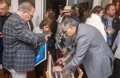 People examining artwork at an indoor gallery event.