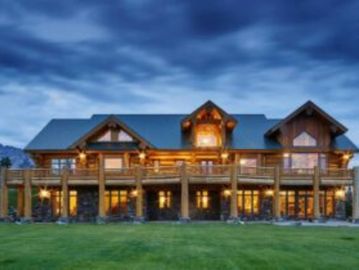 Large wooden cabin with warm lights under a twilight sky.