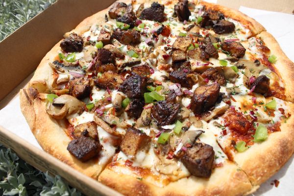 A pizza with jerk pork chunks. pizza delivery available italian restaurant in kingston