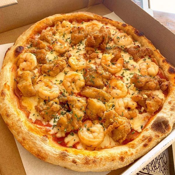 A rich pizza with sauteed shrimp, fish fillet and garlic, on a tomato sauce and mozzarella base.