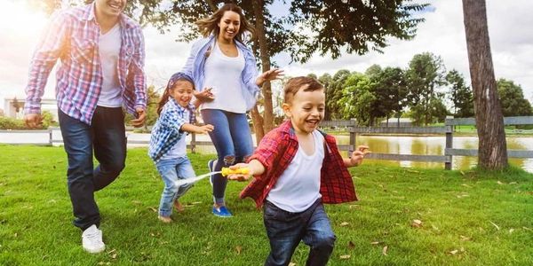 A joyful family playing and running together in a sunny park.
