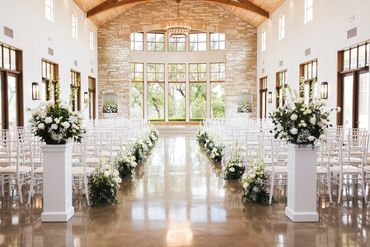Bright wedding venue with white floral decorations and large windows.