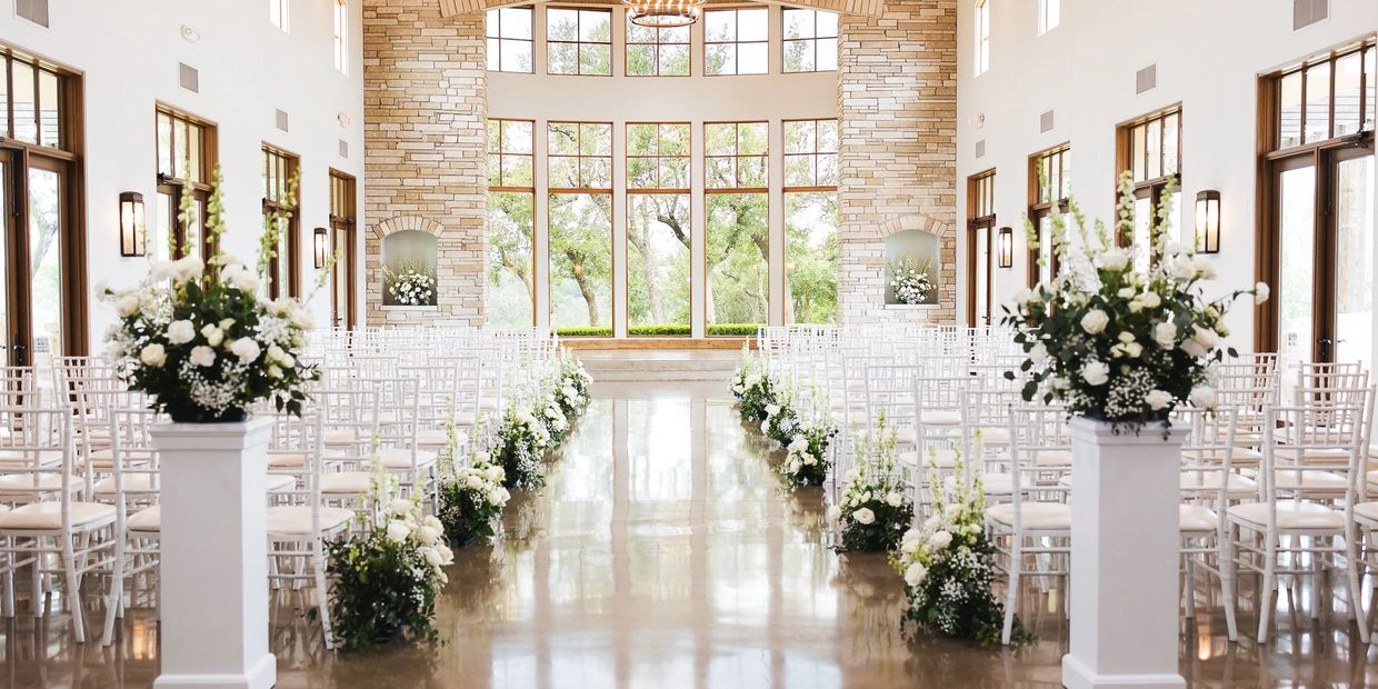 Bright wedding venue with white floral decorations and large windows.