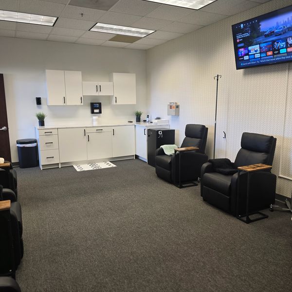 Modern waiting area with black chairs, white cabinets, and a TV mounted on the wall.