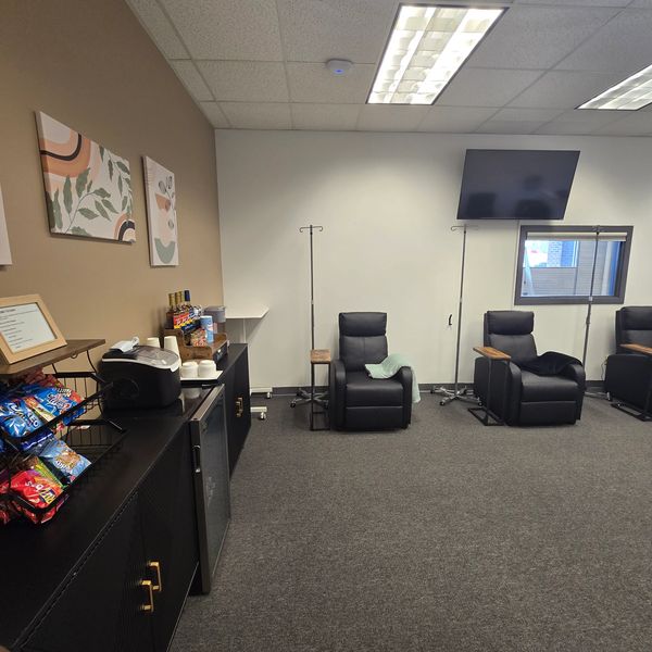 A cozy lounge area with black chairs, snacks, and a TV on the wall.