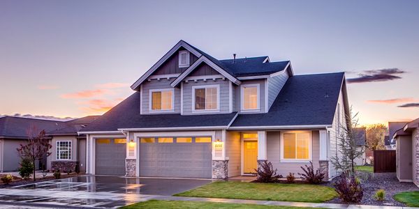 Modern two-story house with a wet driveway at sunset.