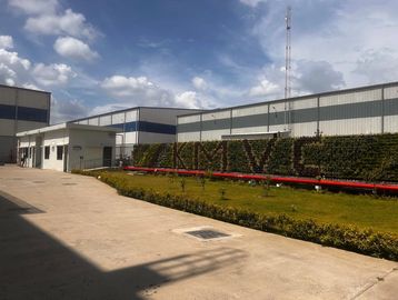 Industrial buildings with a green wall displaying 'KMVIC' under a blue sky.