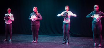 Two girls performing a dance holding hats on stage.