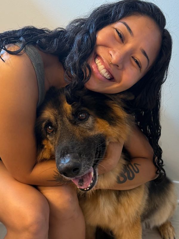 Smiling woman hugging a happy German Shepherd.