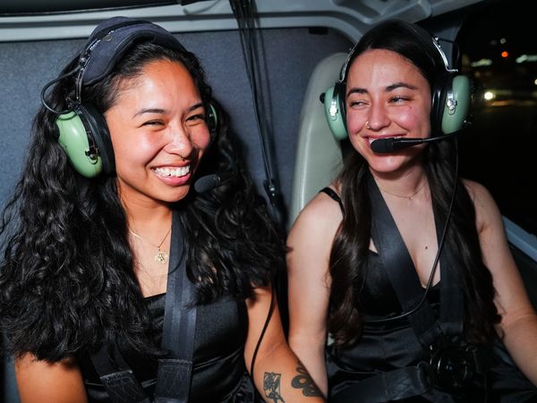 Two women smiling inside an aircraft wearing headsets.