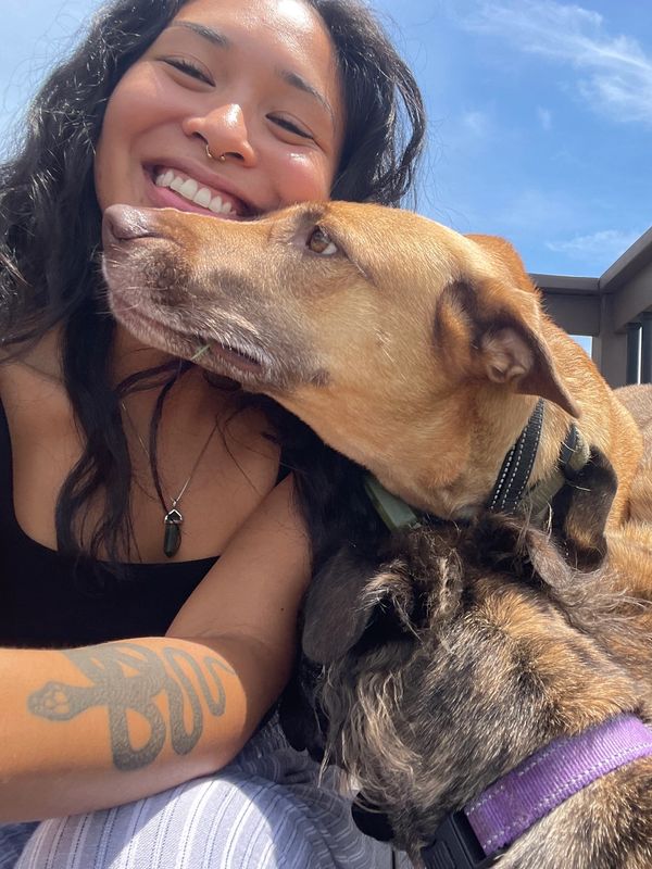 Woman smiling with two affectionate dogs outdoors.