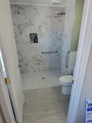 Modern bathroom with marble tiles and a walk-in shower area.