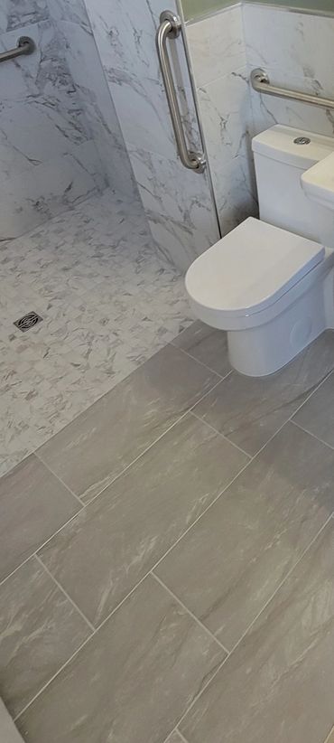 Modern bathroom with marble tiles, a toilet, and a pedestal sink.