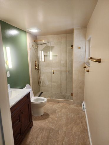 Modern bathroom with glass shower and gold fixtures.