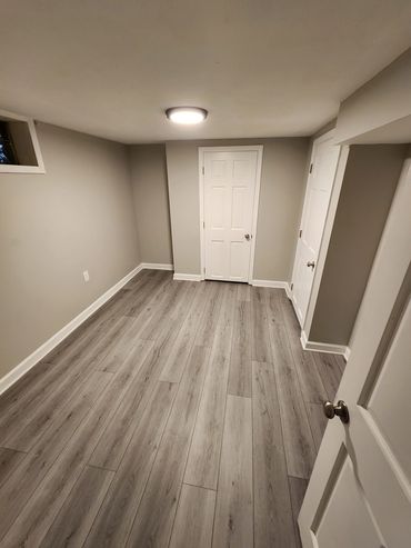 Empty room with light wood flooring and white doors.