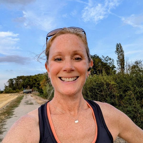 Woman smiling outdoors on a pathway.
