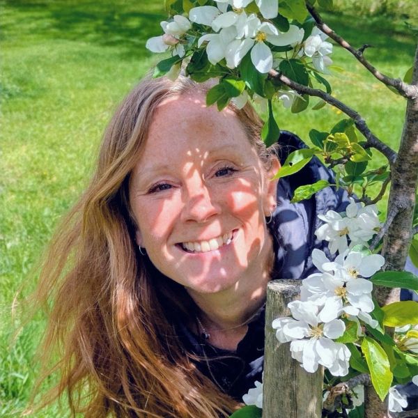 Woman smiling behind a flowering tree branch.