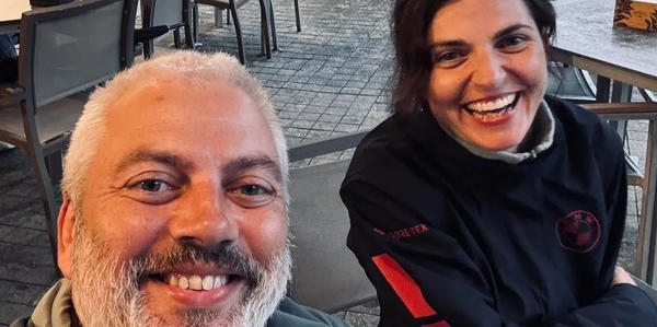 Two people smiling outdoors at a café or restaurant.