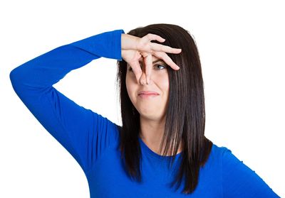 A woman pinching her nose shut with a disgusted look on her face
