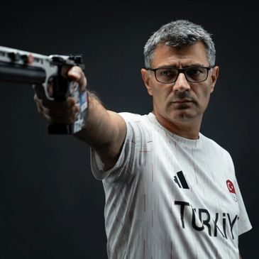 Man in Turkey sports shirt aiming a pistol with focus.