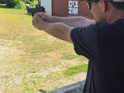 Man aiming a handgun outdoors.