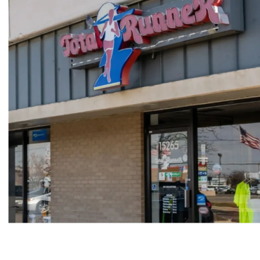 Storefront of Total Runner with a logo and American flag reflection.