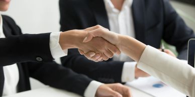 Two businesspeople shaking hands in a professional setting.