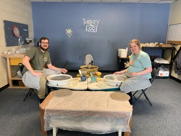 beginner students sitting at the pottery wheel