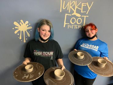 Photo of teens with their wheel thrown pottery wheel
