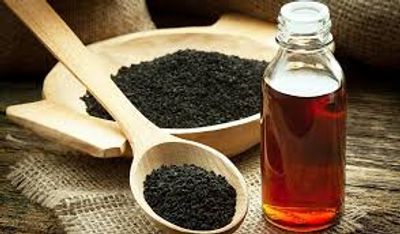 Organic Blackseeds in wooden bowl and spoon and Blackseed Oil bottled on a table