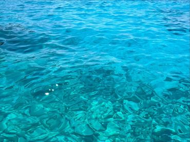 Clear turquoise water over smooth underwater rocks.