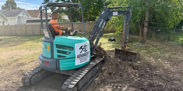 Man operating a small excavator in a backyard construction site.