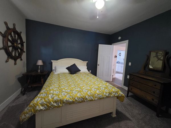 Bedroom with navy blue walls and a yellow floral bedspread.
