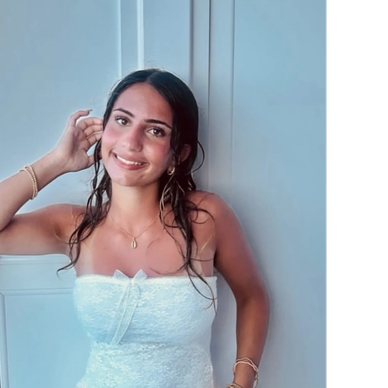 Smiling woman in white top posing indoors.