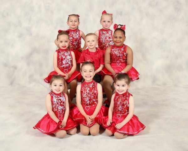 Group of young dancers in red costumes posing for a photo.