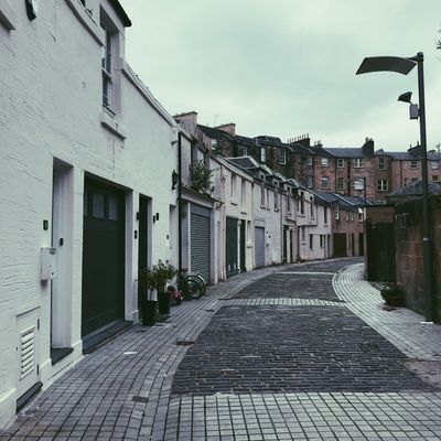 Quiet cobblestone street with white buildings under overcast sky.